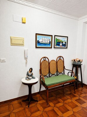 A room with a wooden floor, a green cushioned bench, a small table with a figurine, and two framed paintings on the wall. - 🏖️ Spacious 4-bedroom apartment just a short walk from the beach. ☀️ (Vinaròs)