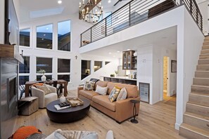 Ein großzügiger Wohnbereich mit hohen Decken, Kamin, Esstisch und einer großen Couch.