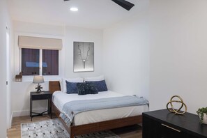 Ein Schlafzimmer mit Bett, Nachttisch, Lampe und Wandbild.