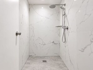 A modern bathroom with a shower, marble walls, and a visible drain. - Cozy Room | Private Shower, Heart of Marrickville (Marrickville)