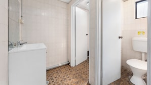 A bathroom with a white sink, a toilet, and a mirror.