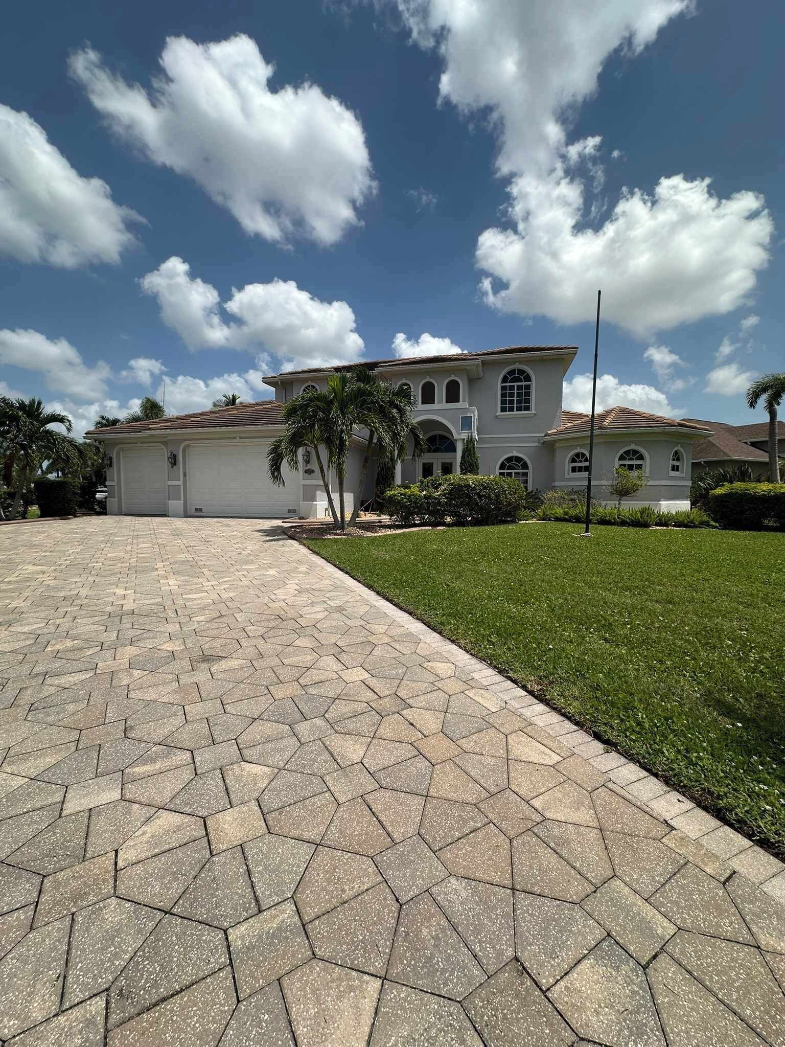 A two-story house with a paved driveway and a well-maintained lawn.