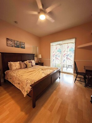 A bedroom with a large bed, a ceiling fan, a window with blinds, and a chair. - Villa Memories - Cape Coral (Cape Coral)