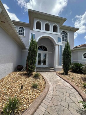 A two-story house with a central entrance, a covered porch, and a landscaped driveway. - Villa Memories - Cape Coral (Cape Coral)