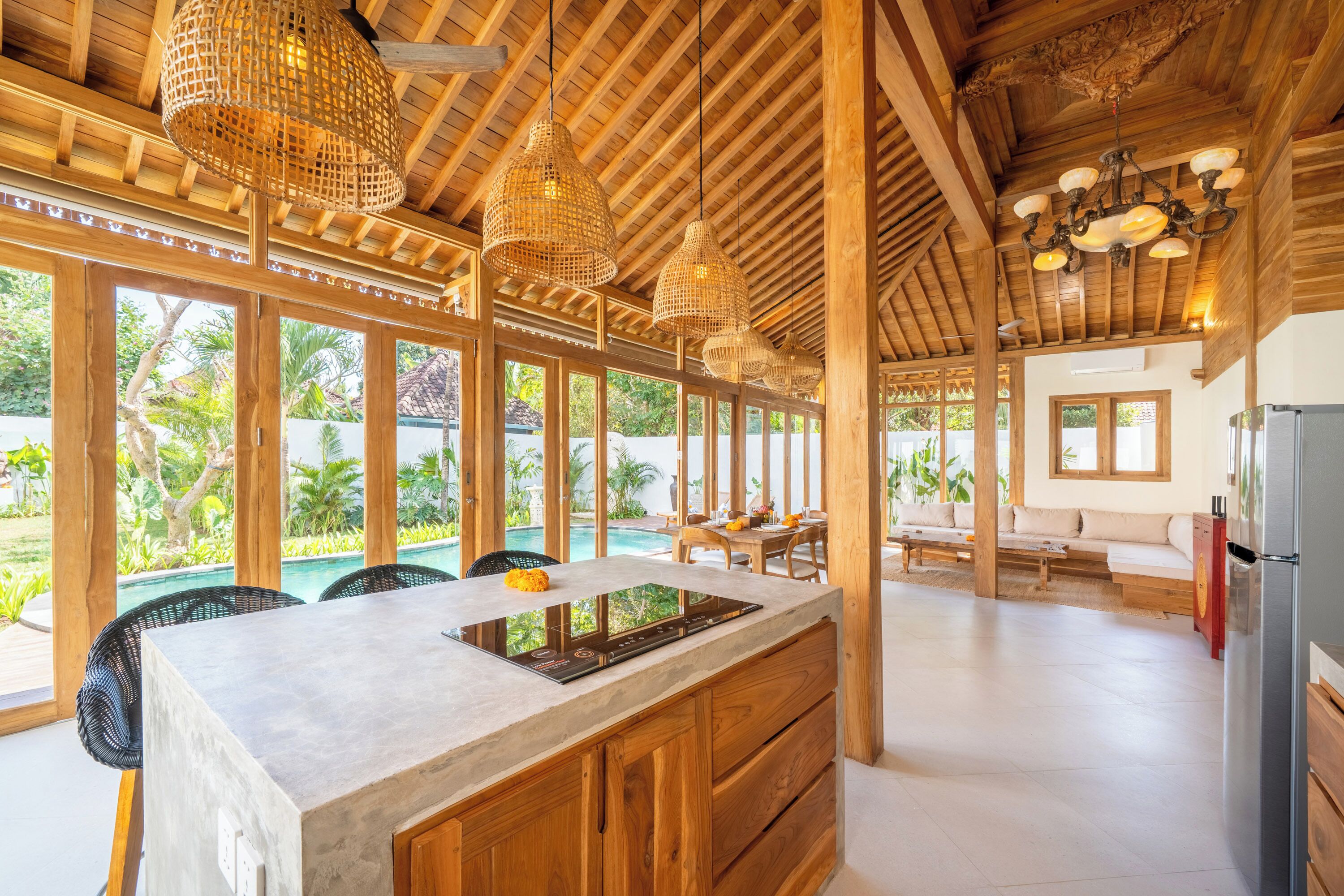 A spacious kitchen with a large island, wooden beams, and a view of a swimming pool.