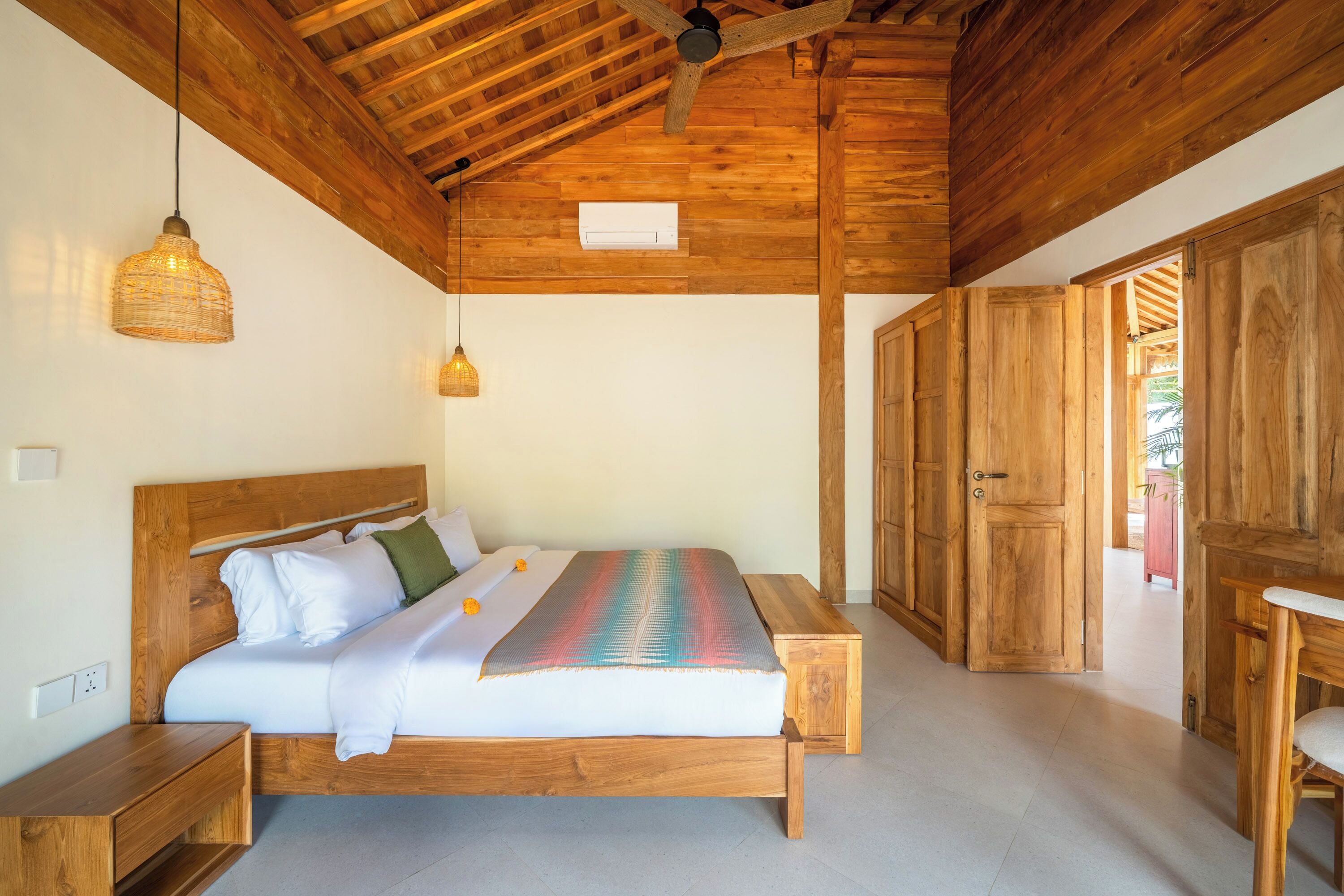 Ein Schlafzimmer mit hölzernem Rahmen, einem Bett, Nachttischen und einem Deckenventilator.
