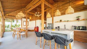 A spacious kitchen with a bar area, wooden ceiling beams, and modern appliances.