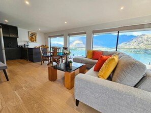 A modern living room with a sofa, coffee table, and dining area. - Elia's House (Queenstown)