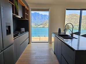 Uma cozinha moderna com vista para um lago e montanhas.
