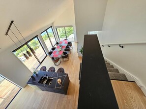 Um interior moderno com área de jantar, uma ilha de cozinha e escada para um andar superior.