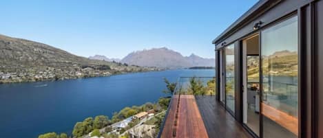Un edificio moderno con amplios ventanales de vidrio que dan a un lago y montañas.