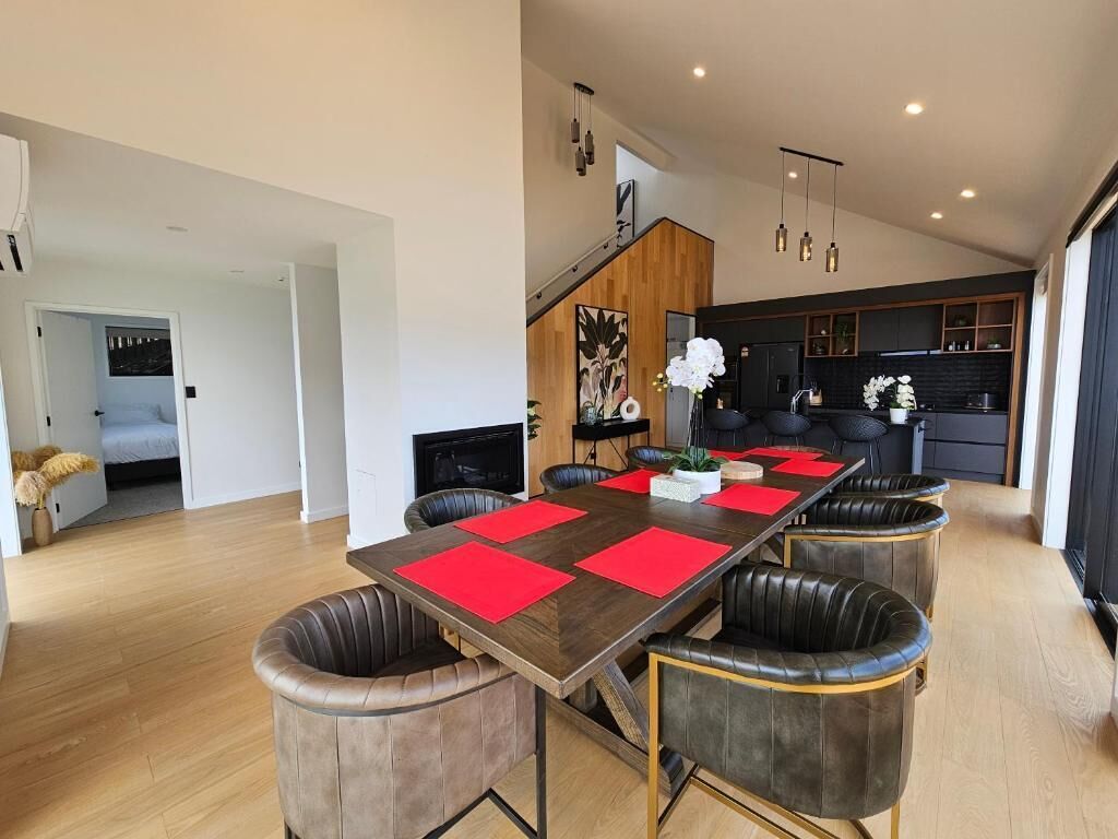 Uma sala de jantar moderna com uma mesa comprida, jogos americanos vermelhos e cadeiras de couro.