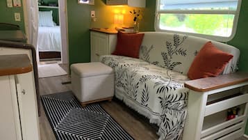 Interior de uma motorhome compacta, com cozinha compacta, sofá com tecido estampado e janela com vista.