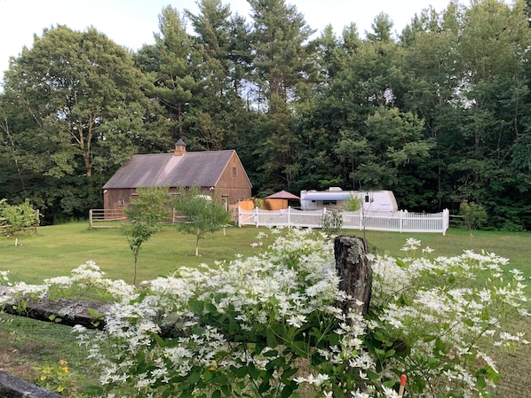 A rural property with a wooden barn, a white fence, and a mobile home.