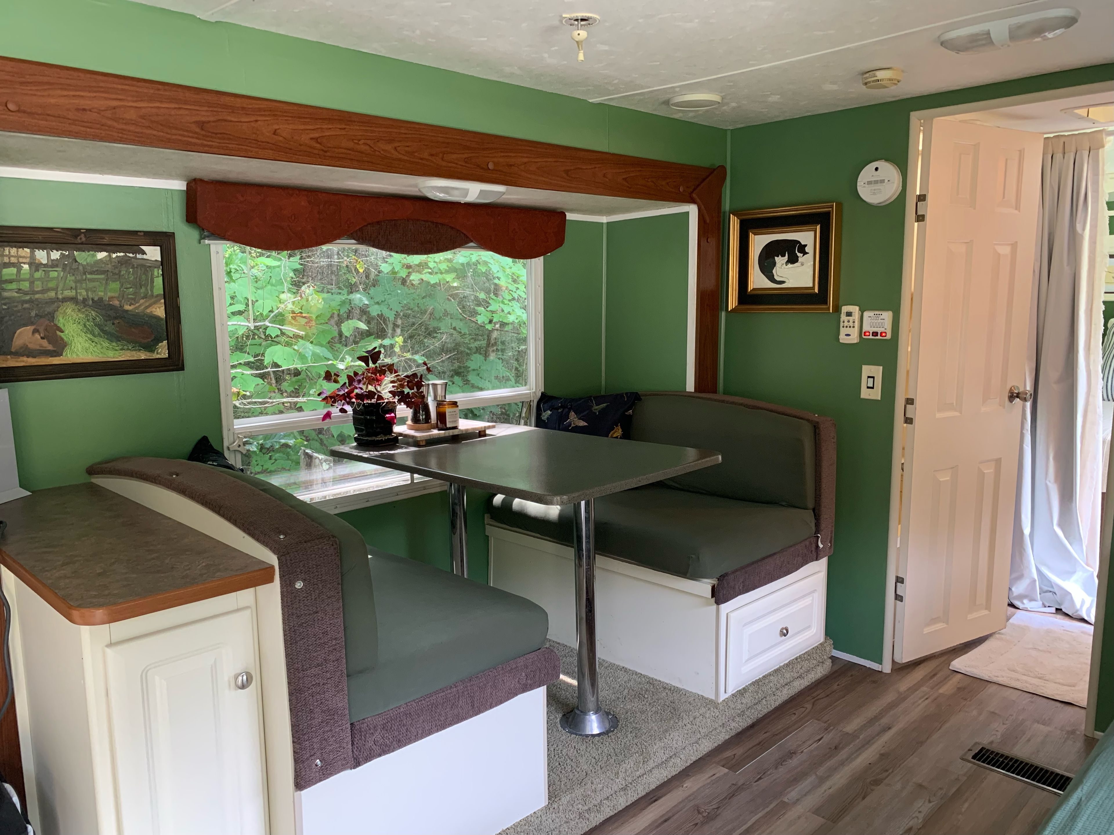Una kitchenette compacta con ventana, una mesa y un banco.