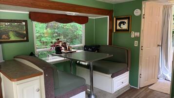 Una kitchenette compacta con ventana, una mesa y un banco.