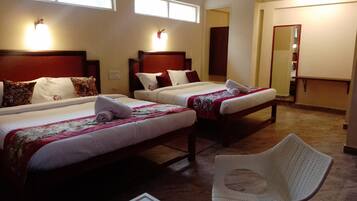 A hotel room with two beds, a chair, and a mirror.