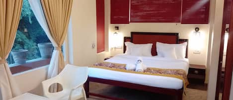 Una habitación de hotel con cama, una silla, ventana con cortinas y ventilador de techo.