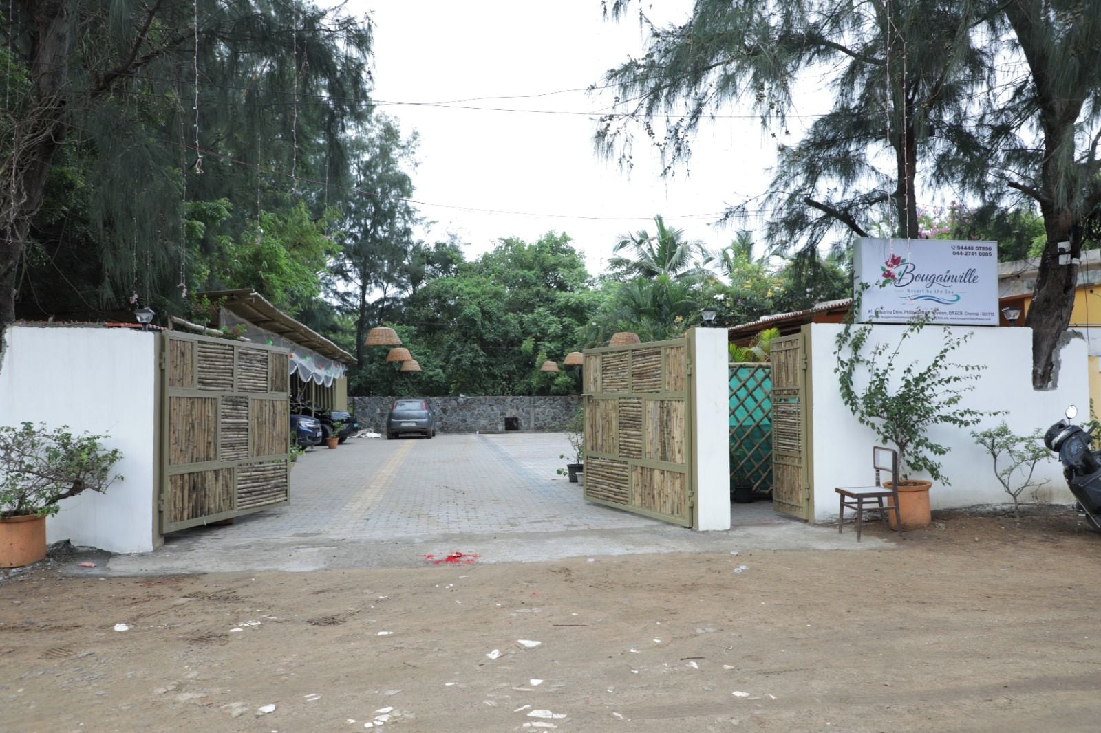 A gated entrance with a sign for 'Bodiamarite' hotel, a paved driveway, and a parked car.
