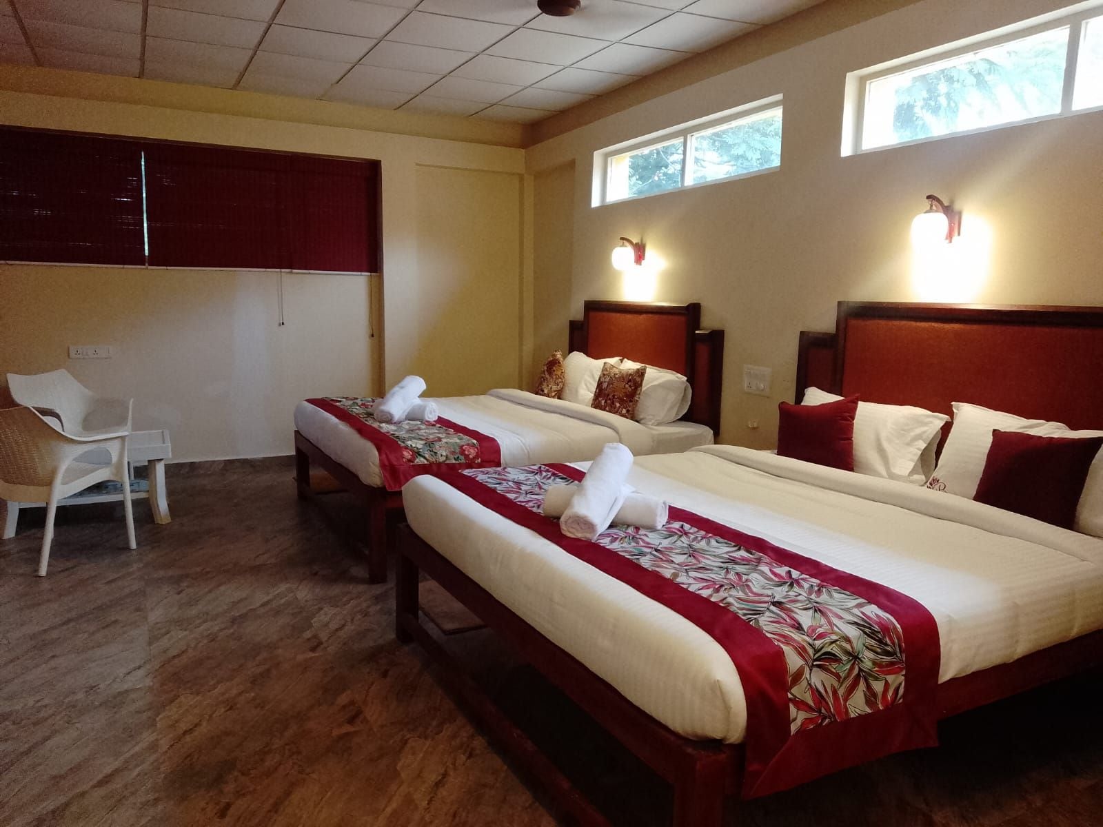 A hotel room with two beds, a chair, and a window.
