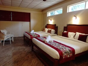 Habitación de hotel con dos camas, una silla y un ventanal.