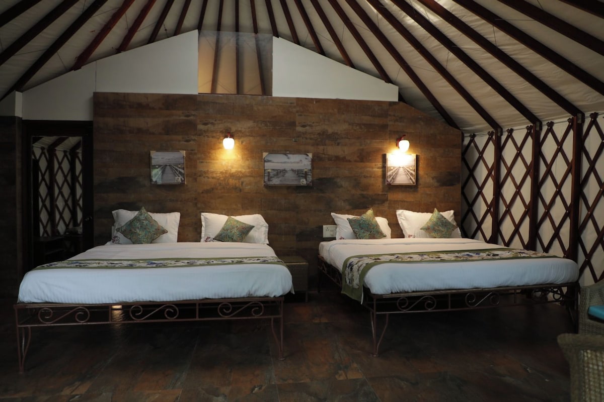 Una habitación con dos camas, paredes de madera y techo inclinado.