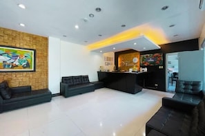 A hotel lobby with a reception desk, seating area, and a large abstract painting on the wall.