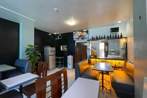 A restaurant with booths and tables, a refrigerator, and a television screen.