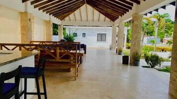 Un patio interior con techo de madera, una barra y diferentes arreglos de asientos.