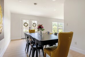 A dining area with a black table, yellow and black chairs, and a vase with flowers. - Sleeps 14 • 7 Beds • Airport • Navy Base• Hospitals • Mall • Beaches (Pensacola)