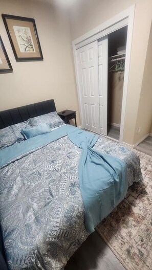 Quarto com cama, mesa de cabeceira, guarda-roupa e porta de acesso a um banheiro.