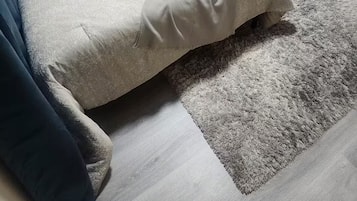 Makuuhuone, jossa on sänky, yöpöytä, ovi ja matto.