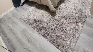 Un dormitori amb un llit, una taula de nit, un quadre i una cortina blava.