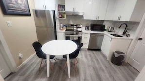 A compact kitchen with white cabinets, a stainless steel refrigerator, a microwave, and a sink.
