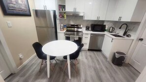 A compact kitchen with white cabinets, a stainless steel refrigerator, a microwave, and a sink.
