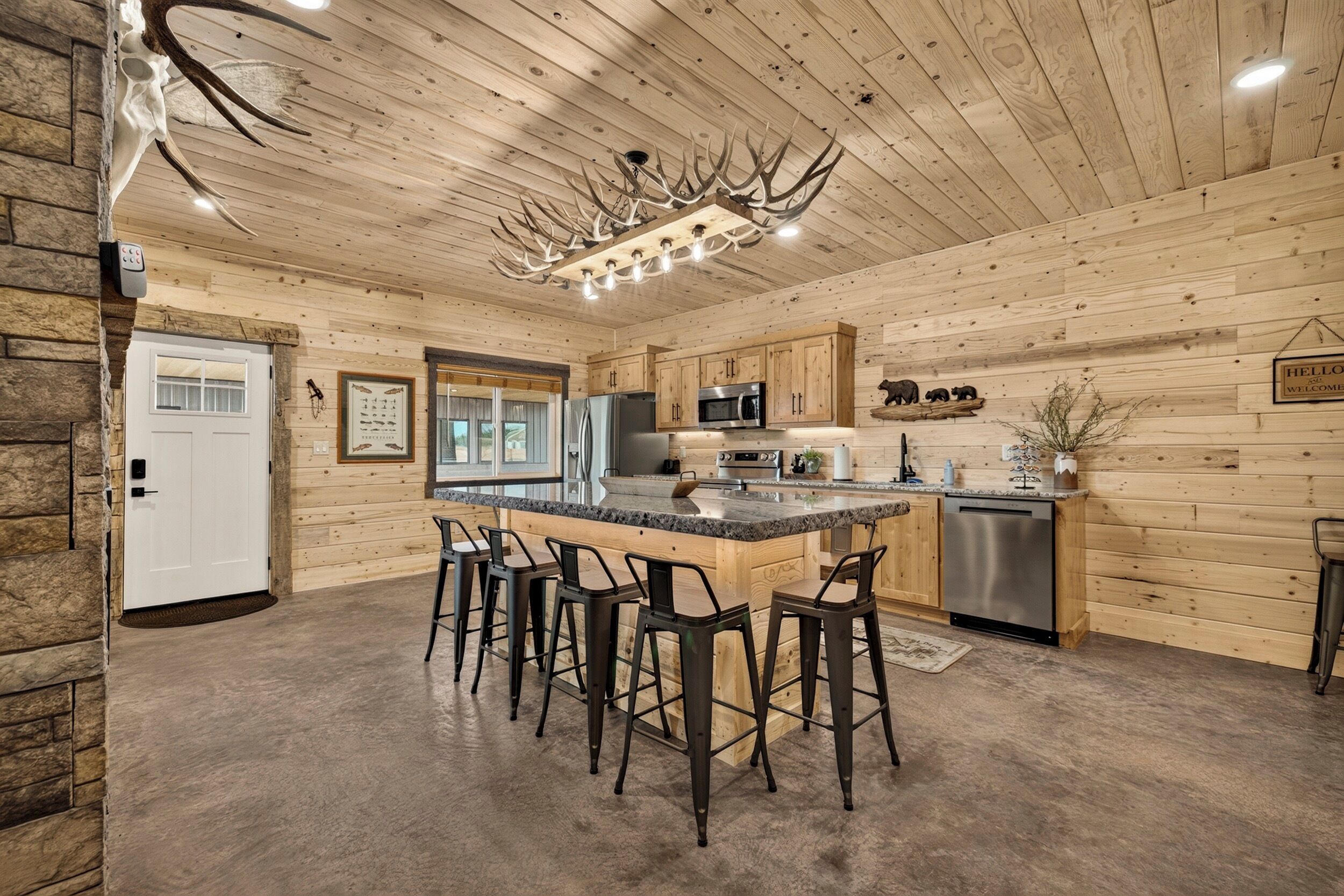 A spacious kitchen with a central island, bar stools, and a stone accent wall.