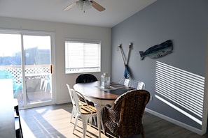 A dining area with a table, chairs, a ceiling fan, and a view through a sliding door. - Enchanting 3BR Soundview | Patio | Firepit | W/D (Camano)