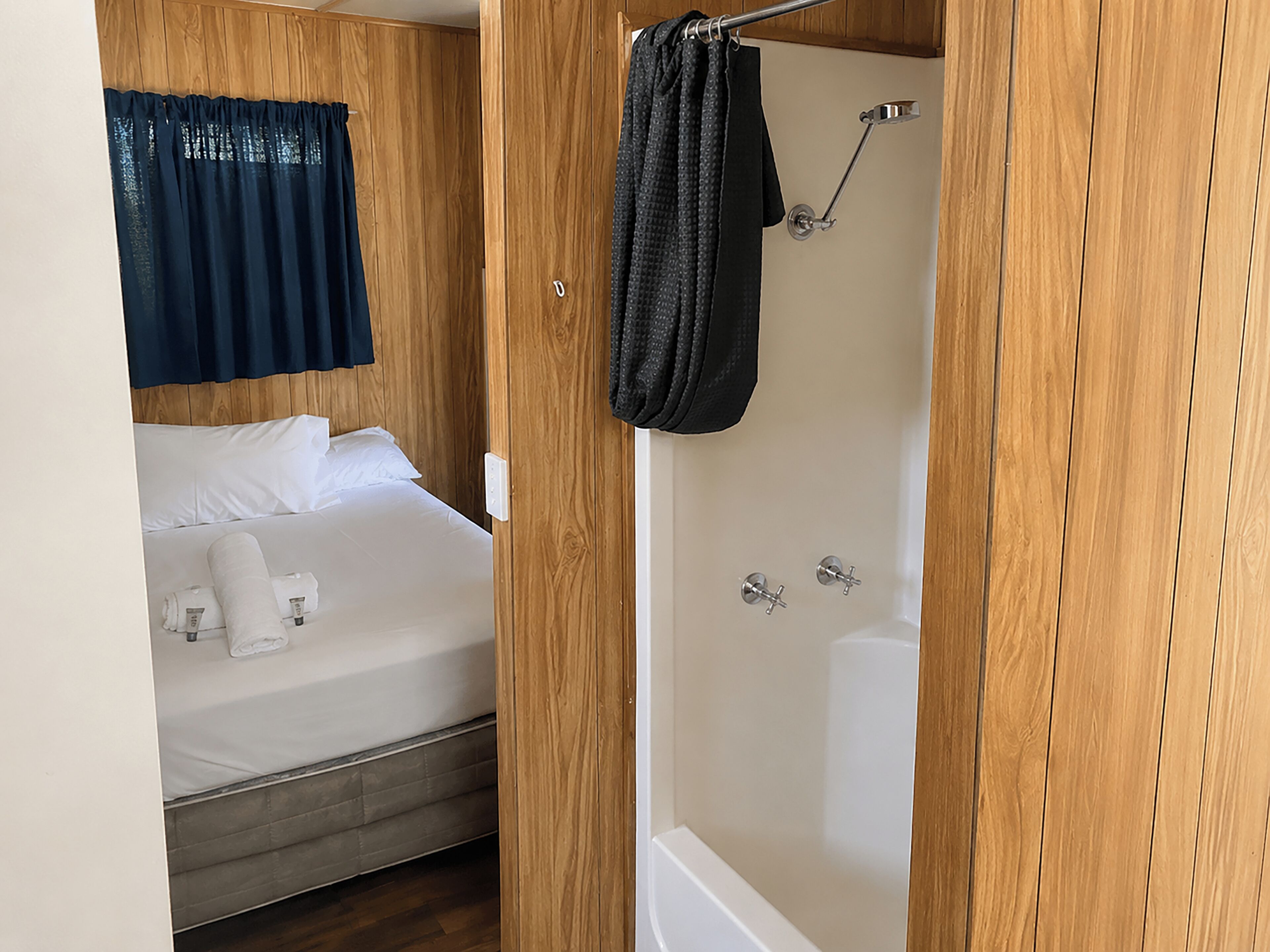 Una habitación pequeña con cama, ducha y cortina.