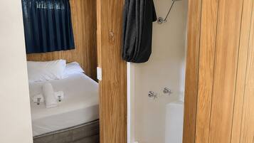 Una habitación pequeña con cama, ducha y cortina.