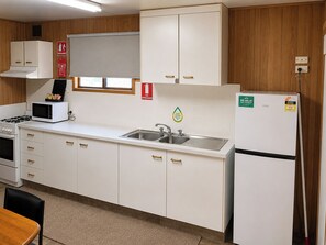 Cocina con armarios blancos, un microondas, un lavabo y un refrigerador.