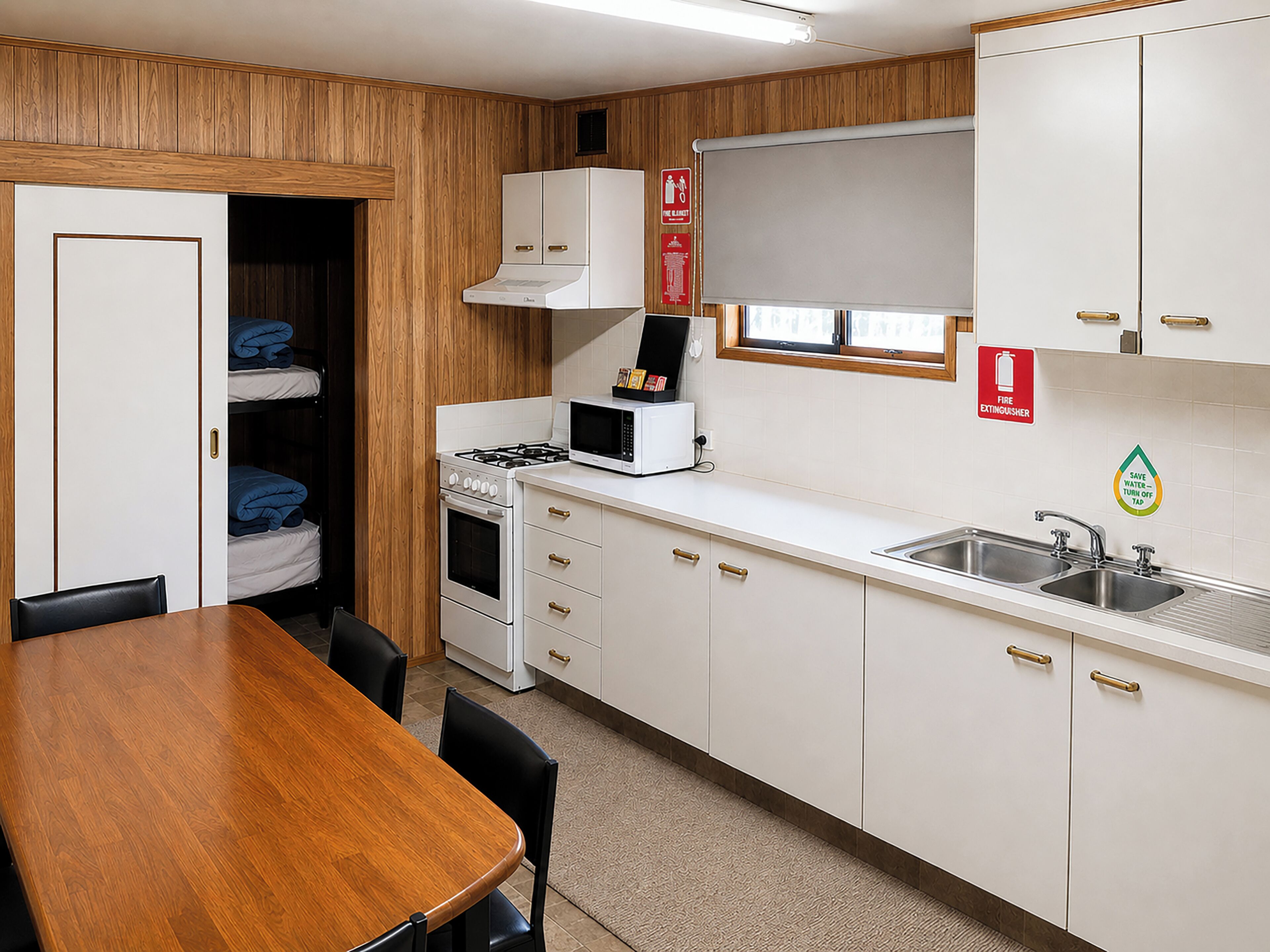 A compact kitchen with a stove, microwave, sink, and a window.