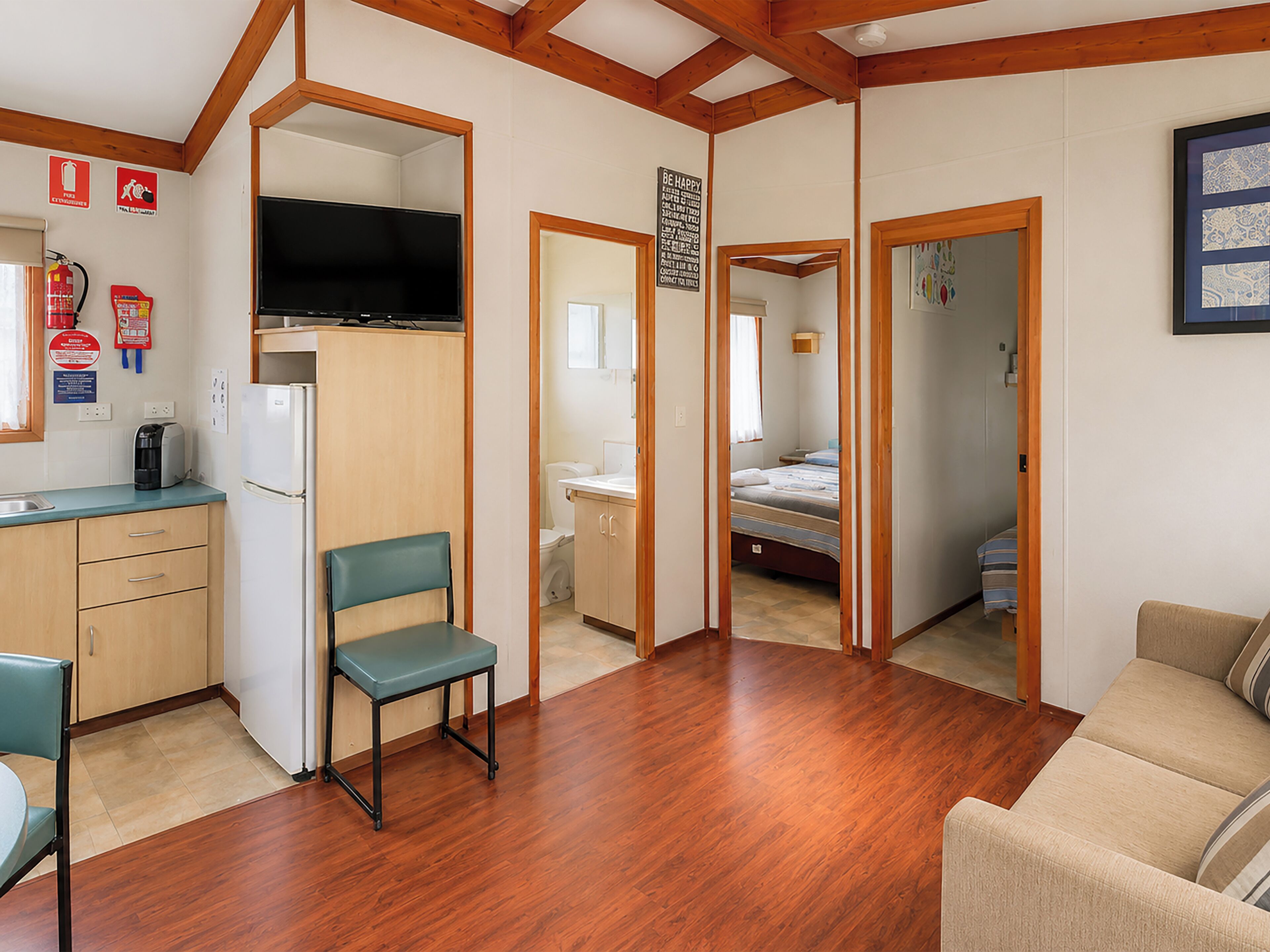 A compact living space with a kitchenette, a television, a dining area, and a bedroom.