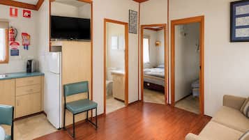 A compact living space with a kitchenette, a television, a dining area, and a bedroom.
