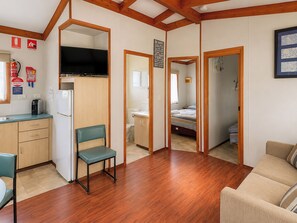A compact living space with a kitchenette, a television, a dining area, and a bedroom.