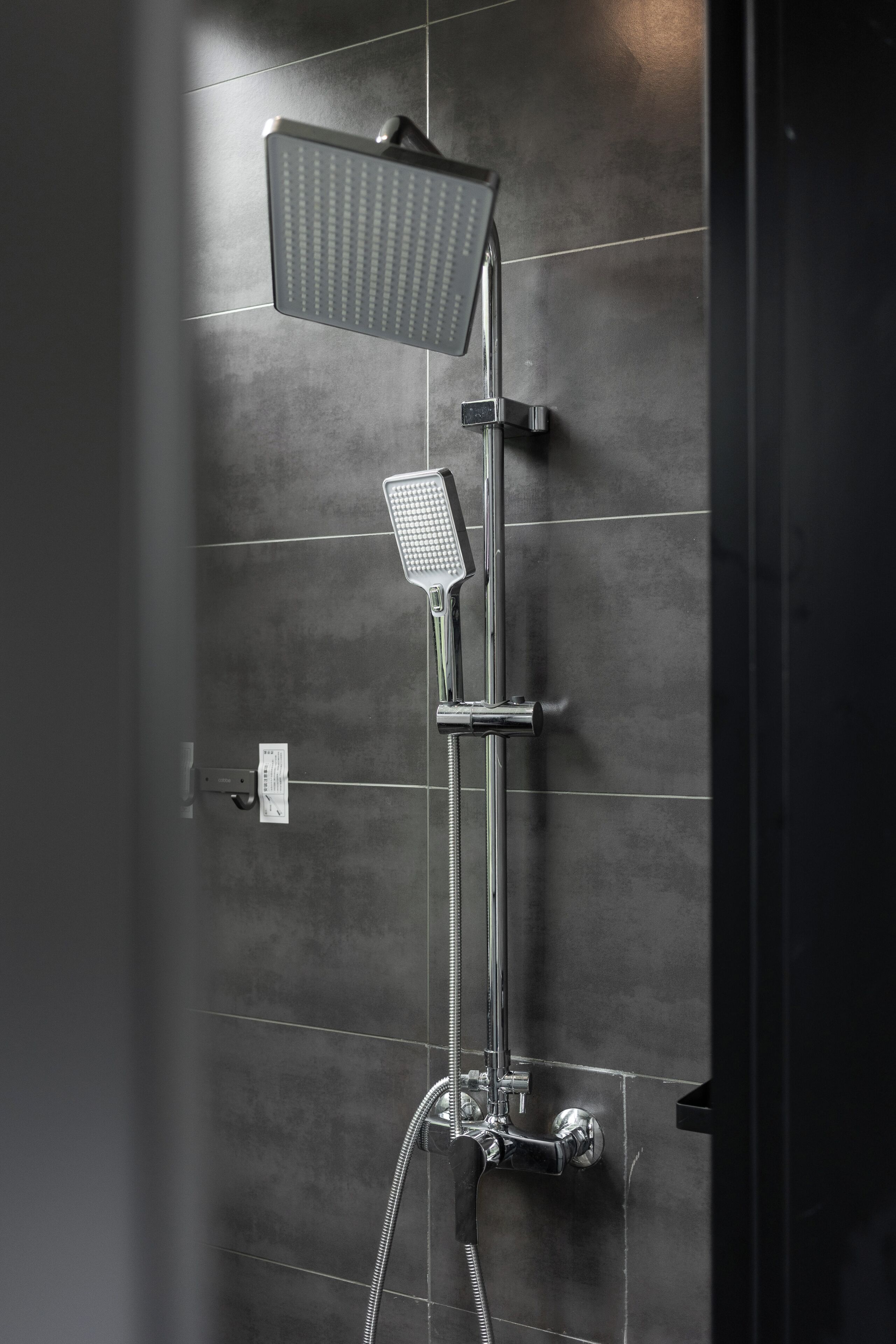 Ducha moderna con cabezal de ducha manual y cabezal de ducha fijo en la pared.
