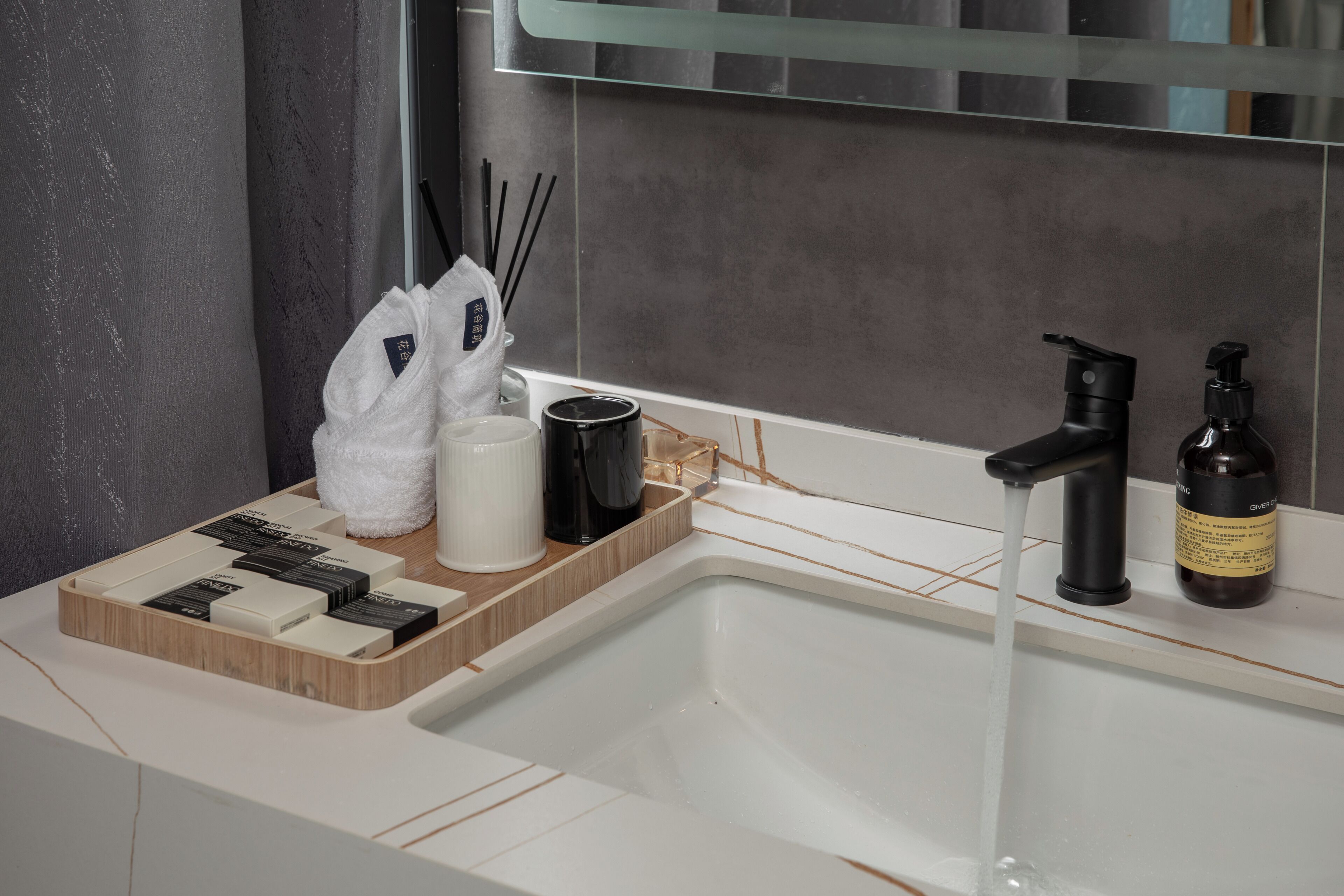 Un baño con un lavamanos blanco, un grifo negro y una botella de jabón en la encimera.
