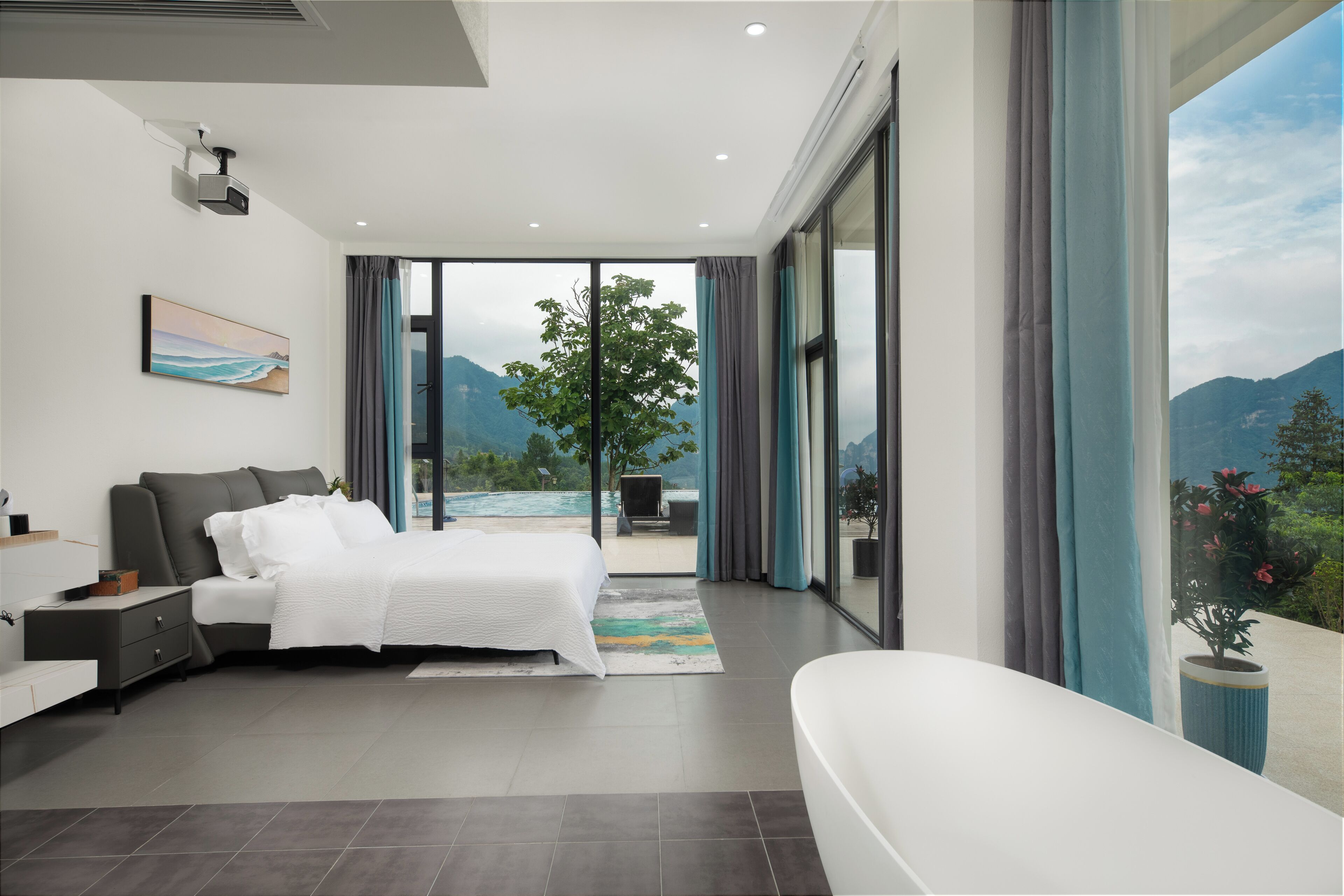 A modern bedroom with a large bed, a bathroom, and a view of mountains through the windows.