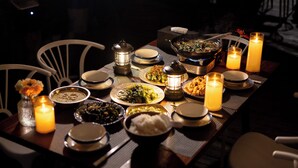 Una mesa de comedor dispuesta con varios platos, velas y una linterna.