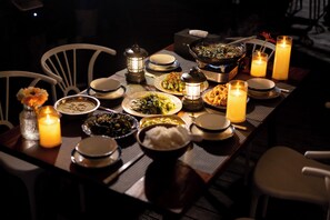 Una mesa de comedor dispuesta con varios platos, velas y una linterna.
