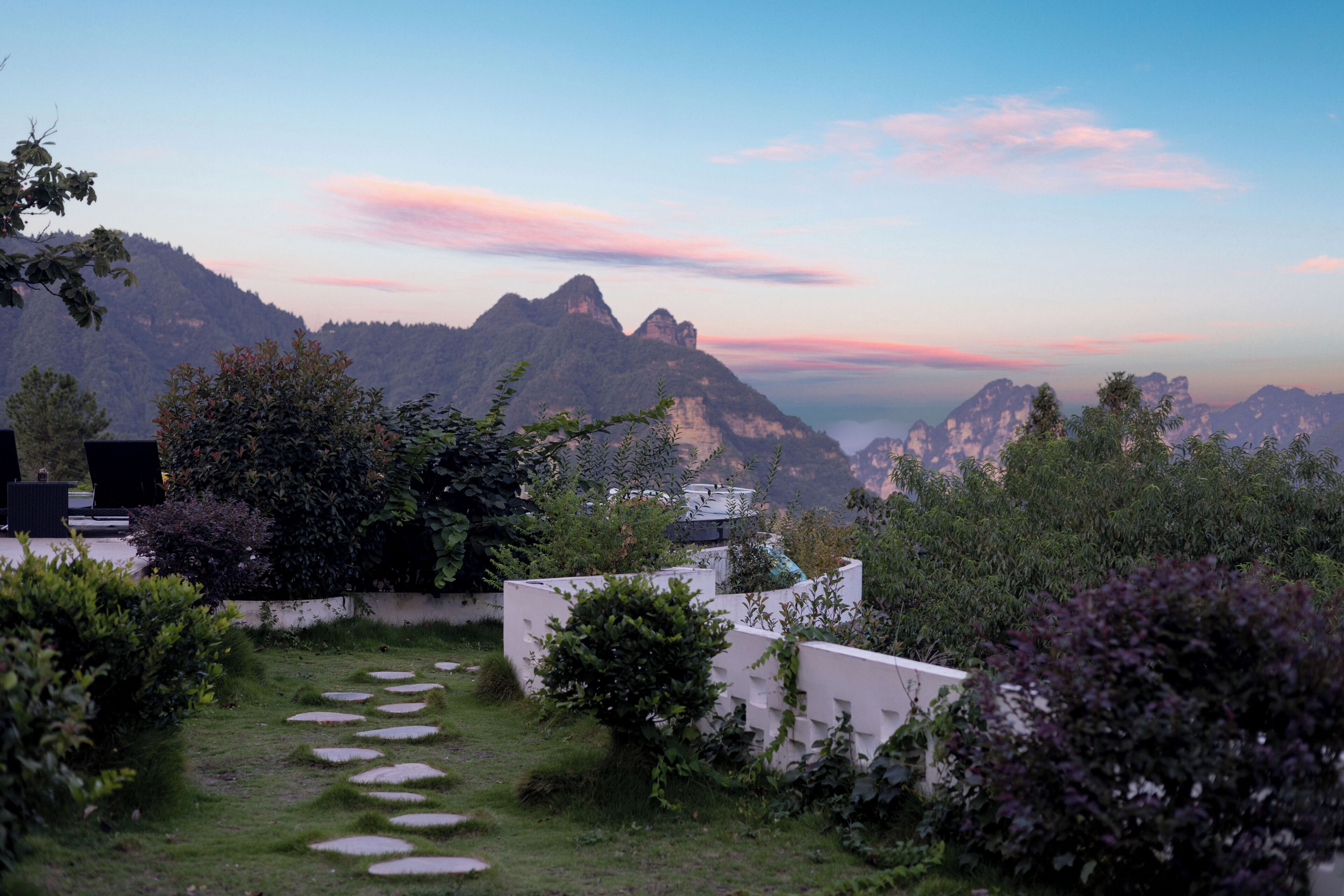 A garden pathway leading to a building with a view of mountains.